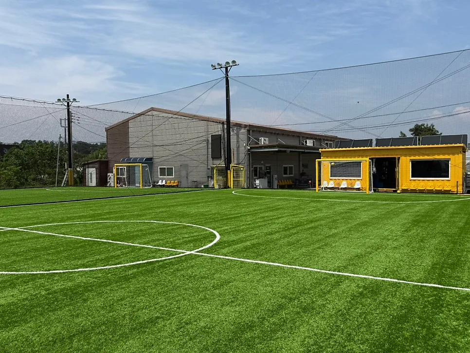 FC Probity's dedicated artificial-turf training ground and clubhouse under a blue sky